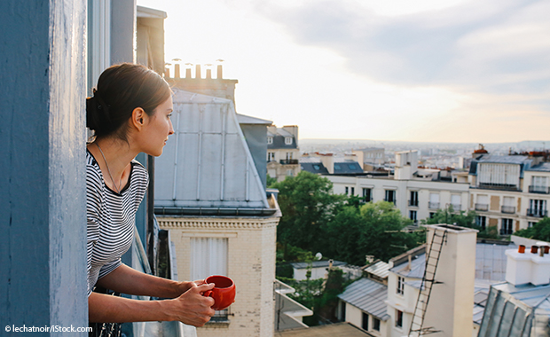 Frau sieht aus einem Fenster über Paris