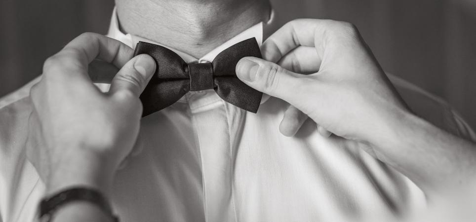 Les mains ajustent un nœud papillon sur le col