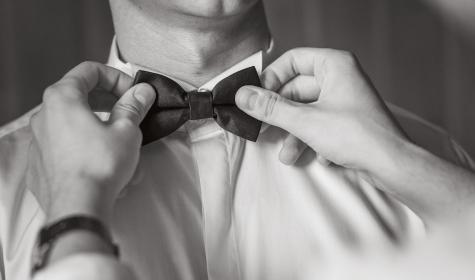 Les mains ajustent un nœud papillon sur le col